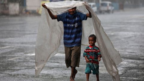 Un padre sin hogar protege a su hijo de la lluvia en busca de un refugio